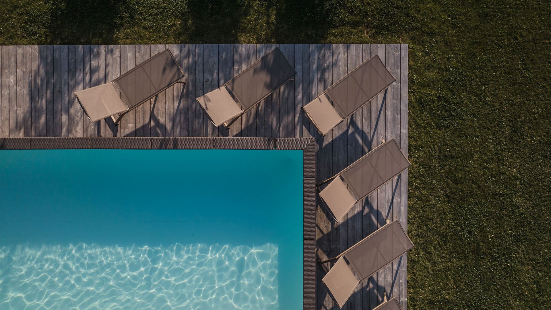 Urlaub in Natz-Schabs? Kessler’s Mountain Lodge! Drohnenansicht eines Pools mit Liegestühlen und Grasflächen