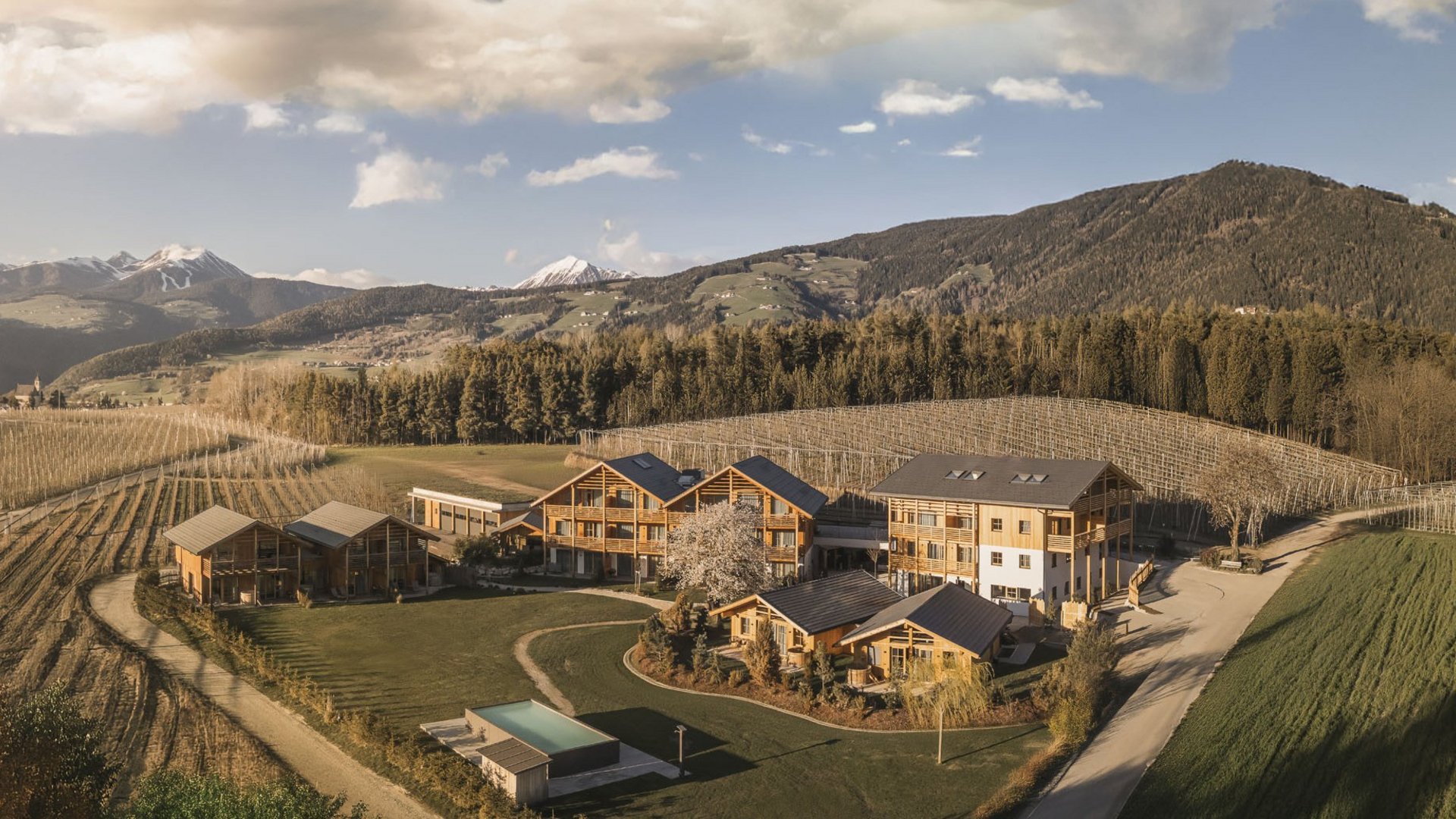 Urlaub in Natz-Schabs? Kessler’s Mountain Lodge! Blick auf einen Hof mit mehreren Holzhäusern und Bergen im Hintergrund