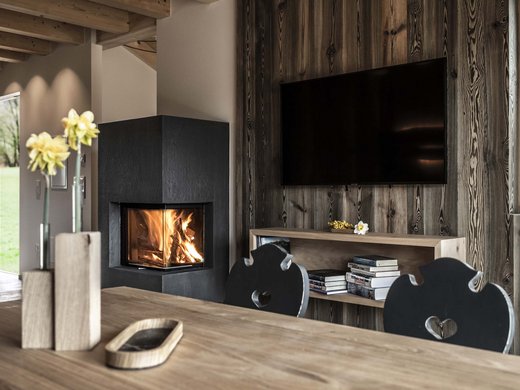 Urlaub in Natz-Schabs? Kessler’s Mountain Lodge! Gemütliches Wohnzimmer mit modernem Kamin und Holztisch mit Blumen