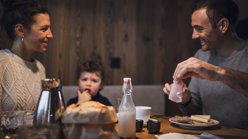 Urlaub in Natz-Schabs? Kessler’s Mountain Lodge! Familie sitzt am Holztisch und frühstückt zusammen in gemütlicher Atmosphäre