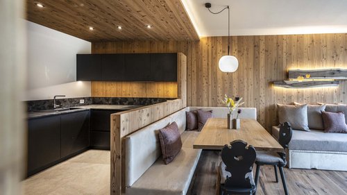 Urlaub in Natz-Schabs? Kessler’s Mountain Lodge! Moderner Wohnbereich mit integrierter Küche und Holzwandverkleidung