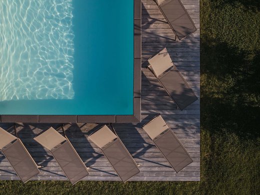 Urlaub in Natz-Schabs? Kessler’s Mountain Lodge! Luftbild eines Pools mit Sonnenliegen auf Holzdeck und Gras umgeben