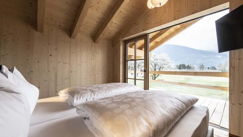 Urlaub in Natz-Schabs? Kessler’s Mountain Lodge! Schlafzimmer aus Holz mit offenem Fenster und Bergblick