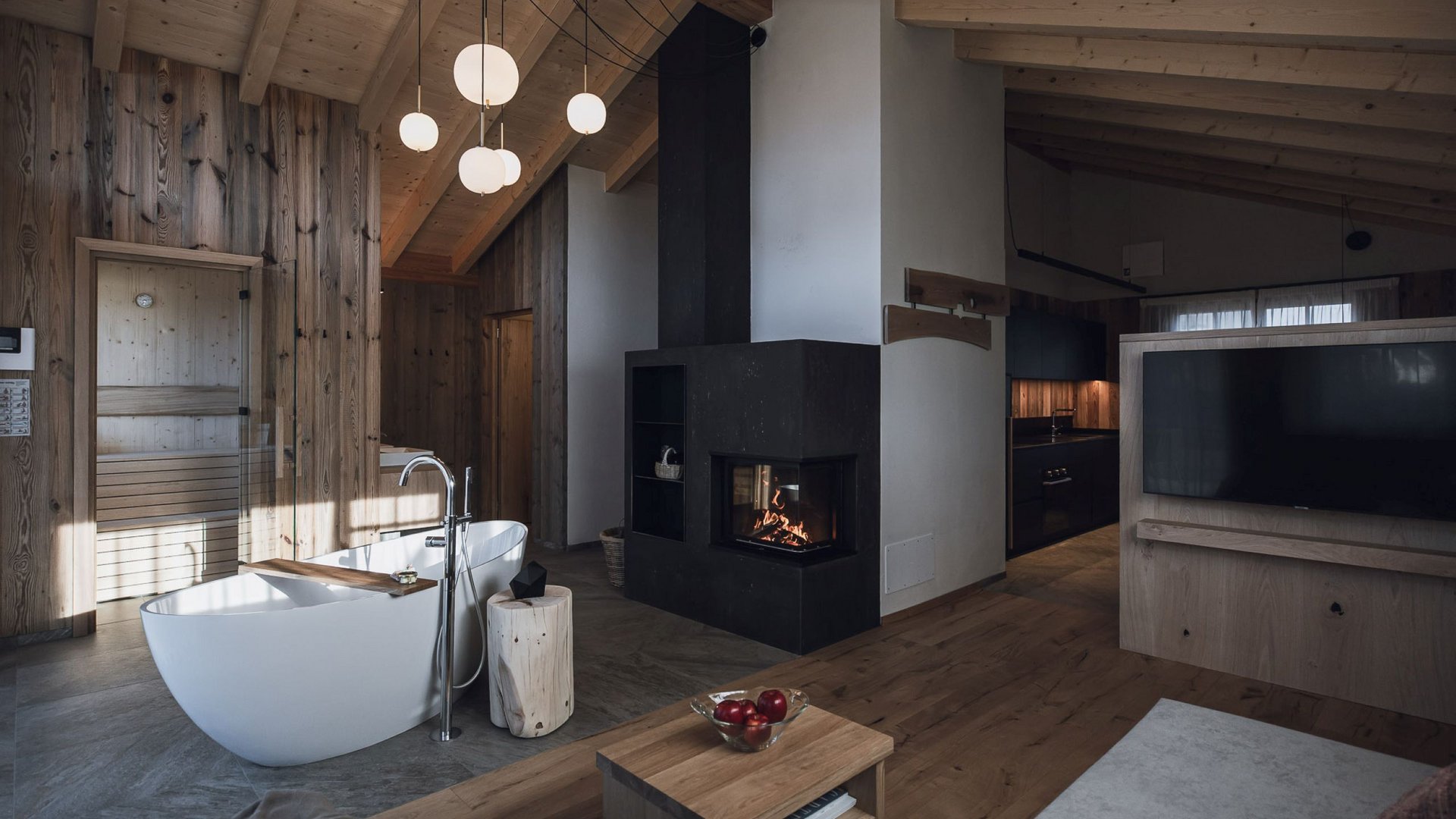 Urlaub in Natz-Schabs? Kessler’s Mountain Lodge! Modernes Wohnzimmer mit Holzdecke, Kamin, freistehender Badewanne und Fernseher