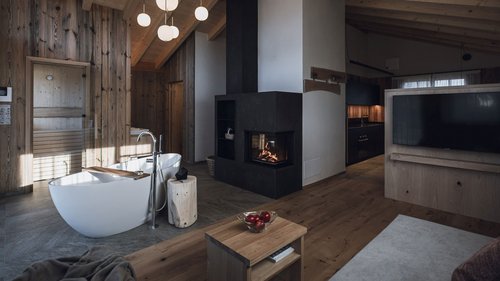 Urlaub in Natz-Schabs? Kessler’s Mountain Lodge! Modernes Wohnzimmer mit Holzdecke, Kamin, freistehender Badewanne und Fernseher