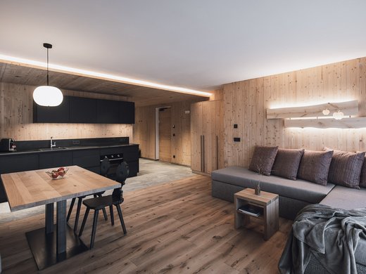 Urlaub in Natz-Schabs? Kessler’s Mountain Lodge! Modernes Wohnzimmer mit offener Küche und Holzwänden