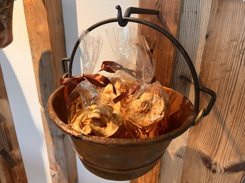 Alpine chalet in South Tyrol with a farm shop Dried apple slices in plastic bags with brown ribbons in a copper pot